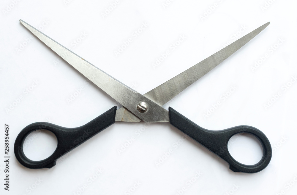 A pair of sharp metal cutting scissors with the cutting blades open. scissors for craft isolated against a white background. Black handle. A pair of sharp metal cutting scissors with the cutting blades open. scissors for craft isolated against a white background. Black handle.