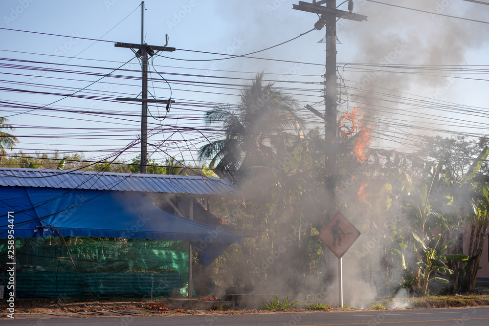 power pylon overload or electric short circuit at transformer on poles and  fire or flame with smoke on blue sky. Problem with electricity in Thailand  Stock Photo
