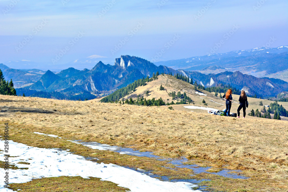 Two young tourist women  looking at amazing  mountains in early spring, travel concept, Pieniny mountains, Szczawnica, Poland