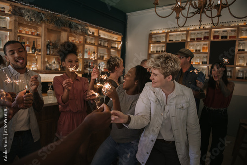 Group of friends celebrating with sparklers in a bar