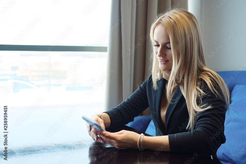 beautiful young woman with phone sitting at a table in a cafe. beautiful young woman with phone sitting at a table in a cafe.