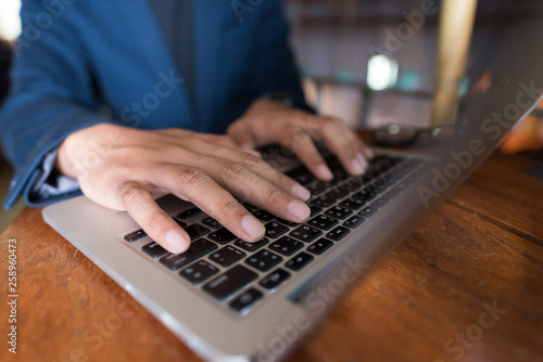 Close up Asian business man using laptop for working in coffee shop in selective focus.