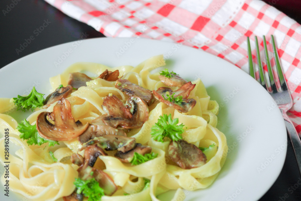 Italian pasta with mushrooms and greens on a dark background