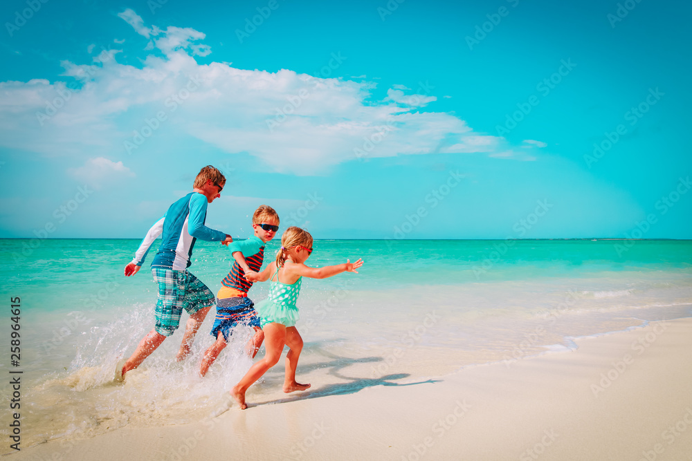 father with kids play with water run on beach