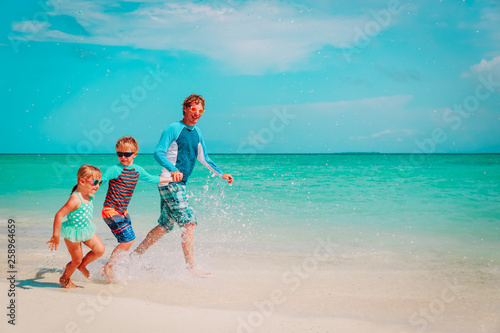 father with kids play with water run on beach