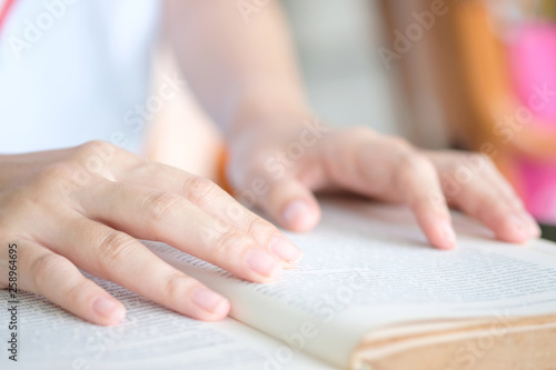 Hand of beautiful woman smiling happily and holding a book reading in the library. On weekends