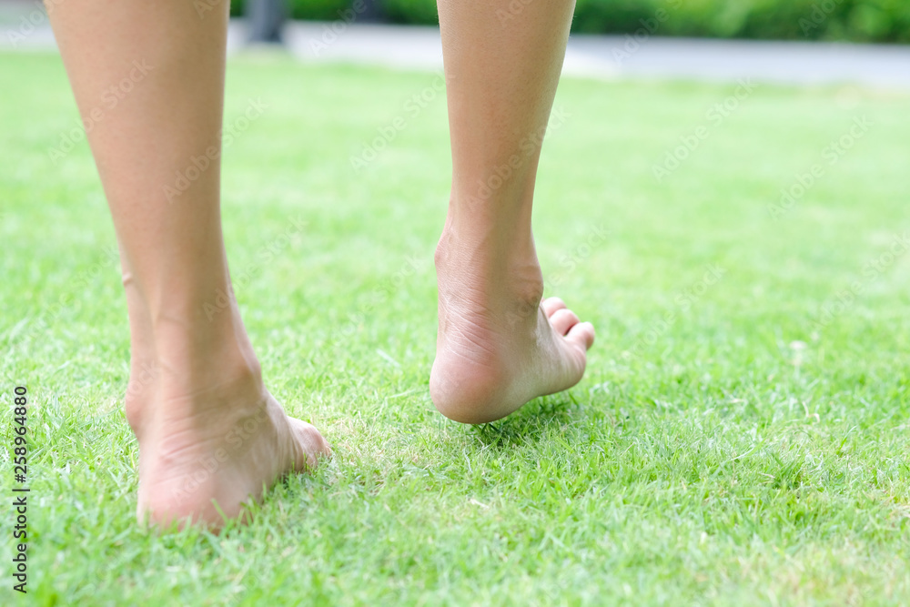 Leg of woman is on the ground. She is about to walk down the grass to exercise in the morning. Health and Relaxation Concepts