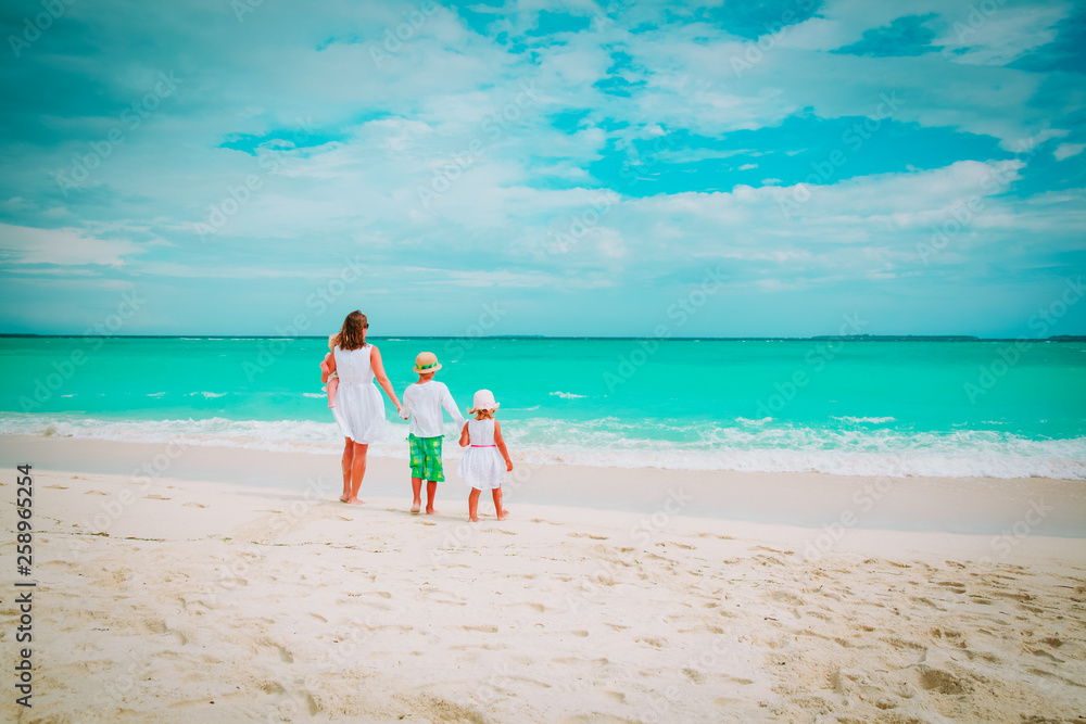 mother with three kids walk on beach