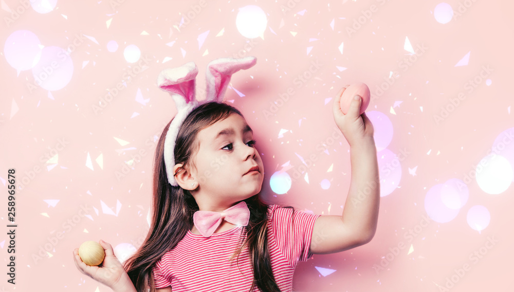 Close up portrait of Cute little girl with colorful topping on face on pink background. Easter child portrait, funny emotions, surprise. Copyspace for text.
