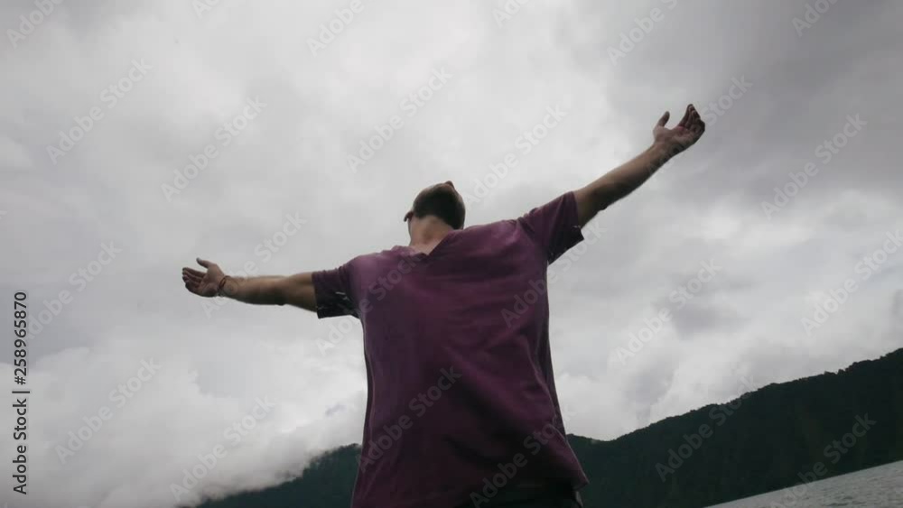 Man standing in boat with his hands raised to sky Man standing in boat with his hands raised to sky