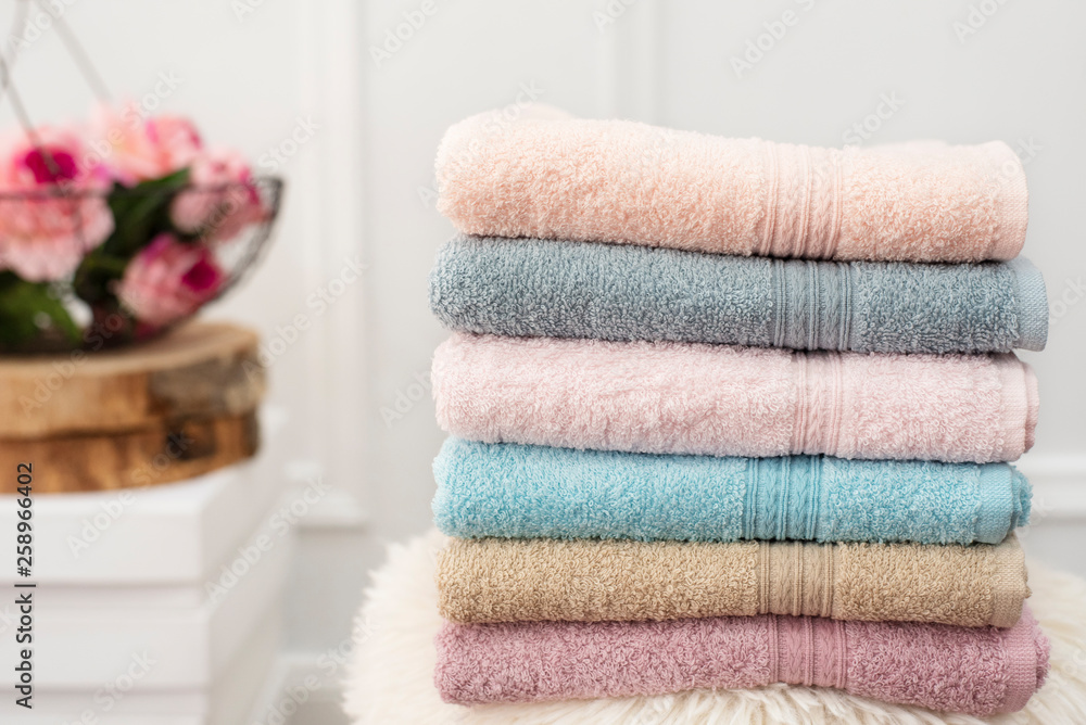 Stack of clean soft colorful towels. Flowers on background Stack of clean soft colorful towels. Flowers on background