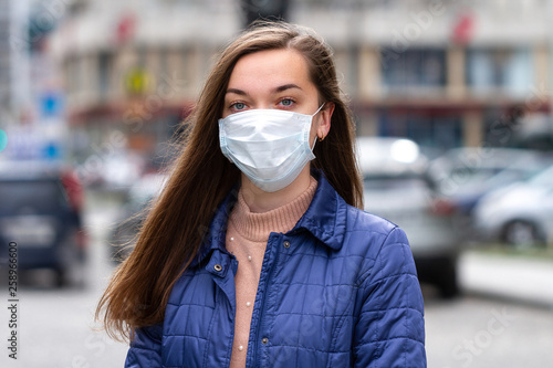 Woman in mask on street because of air pollution and epidemic in city. Protection against virus, infection, exhaust and industrial emissions