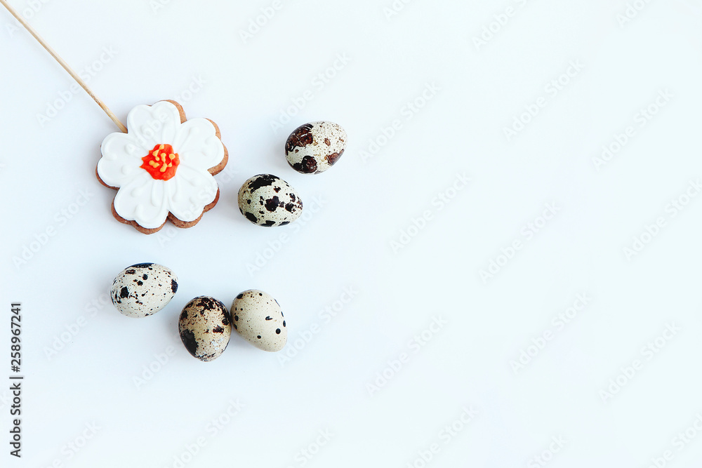 five speckled quail eggs and gingerbread in the form of a flower on a white background Easter concept top view