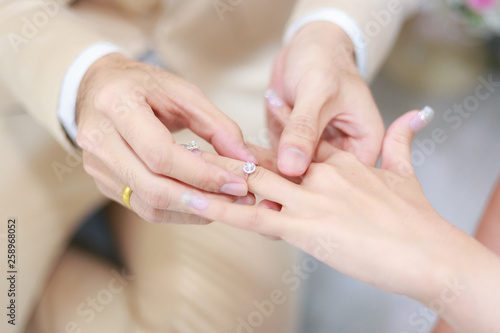 groom wears ring on bride s finger in wedding ceremony
