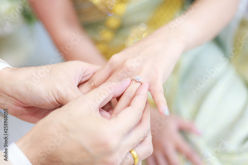 groom wears ring on bride s finger in wedding ceremony