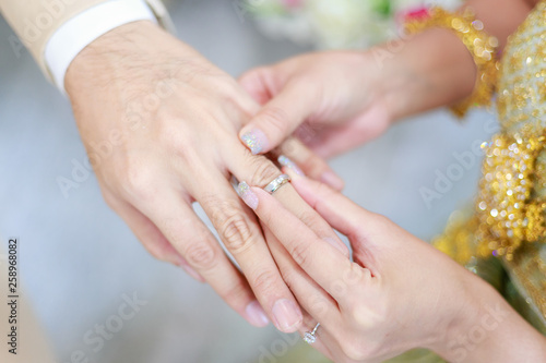 groom wears ring on bride's finger in wedding ceremony
