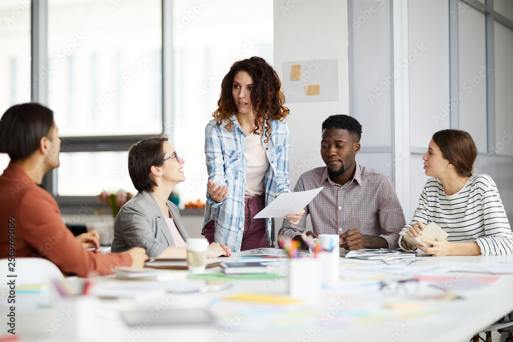 Portrait of contemporary woman talking to multi-ethnic team during meeting in office, copy space Portrait of contemporary woman talking to multi-ethnic team during meeting in office, copy space