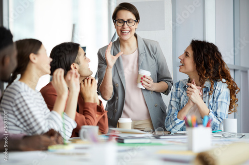 Portrait of smiling team leader talking to group of young businesspeople in meeting, copy space