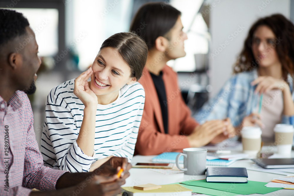 Portrait of smiling young woman talking to African-American colleague during meeting in office, copy space Portrait of smiling young woman talking to African-American colleague during meeting in office, copy space