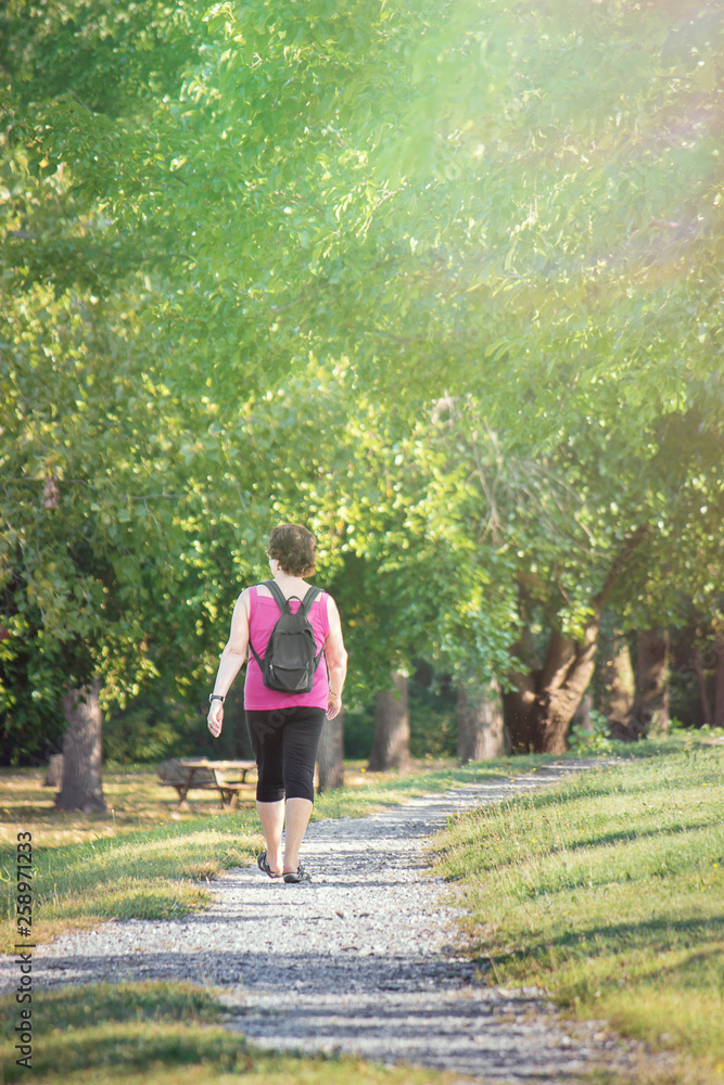 Sportive woman walking in a park. Healthy Lifestyle in the nature (vertical image with copy space) Sportive woman walking in a park. Healthy Lifestyle in the nature (vertical image with copy space)