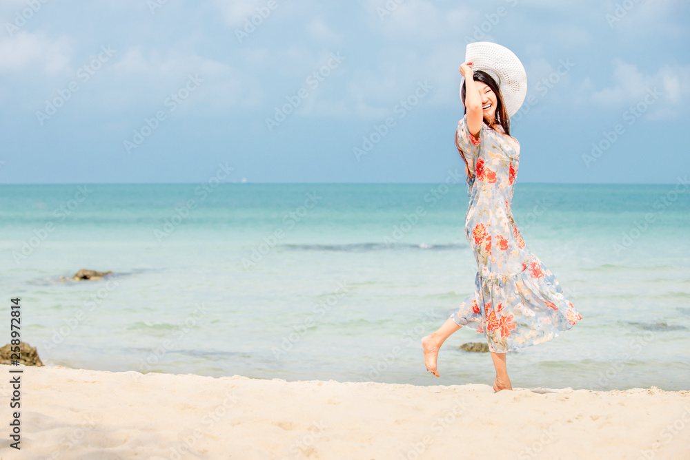Happy traveler asia woman in dress holding sun hat standing on beach enjoys her tropical vacation Happy traveler asia woman in dress holding sun hat standing on beach enjoys her tropical vacation