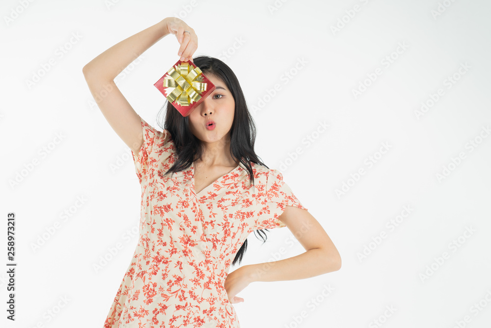 Curious woman in red dress rejoicing her birthday or new year gift box. Young woman holding gift  box with red bow being excited and surprised  holiday present isolated white  background