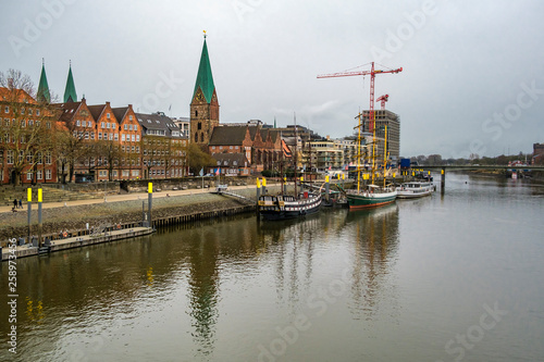 Alexander von Humboldt tall ship and others wooden sailing ships and barg floating on the banks of the River Weser. St. Martini church on the background. Bremen, Germany. March 2019