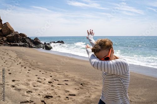 Adult caucasion woman does a dabbing dance move while on the beach. Taken at Point Dume Malibu California photo