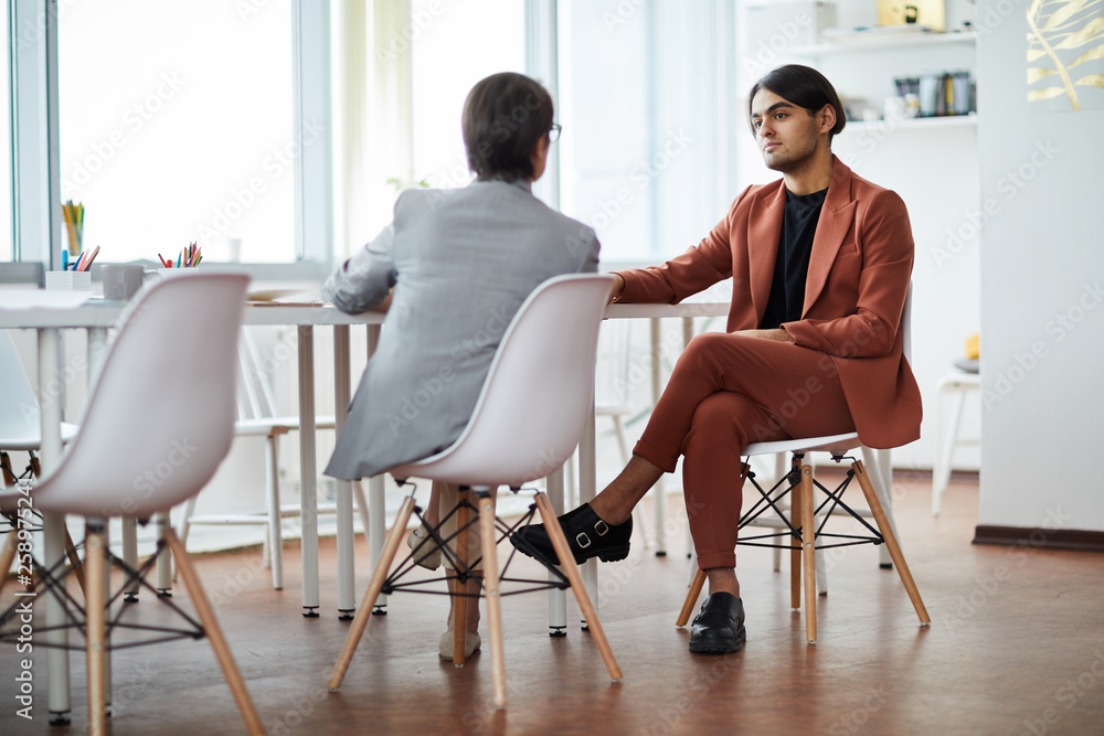 Full length portrait of contemporary Middle-Eastern man listening to HR manager during job interview in office, copy space Full length portrait of contemporary Middle-Eastern man listening to HR manager during job interview in office, copy space