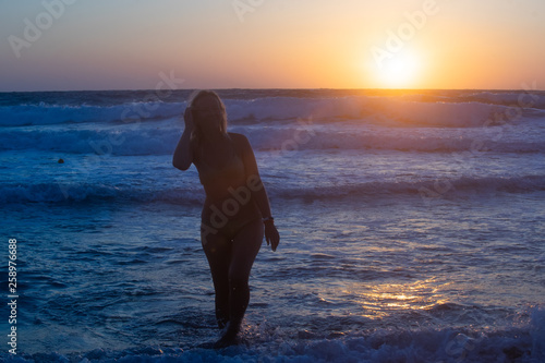 Girl at sunset rejoices sea on the beach