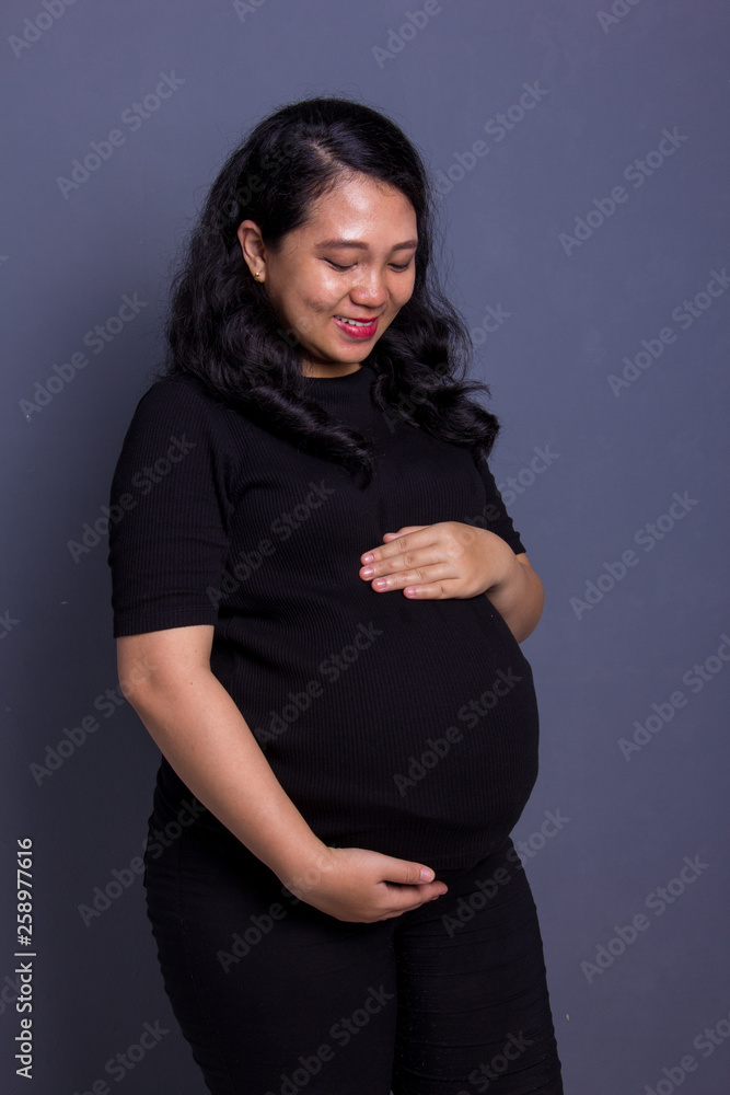 Pregnant mom watching her belly, grey background Pregnant mom watching her belly, grey background