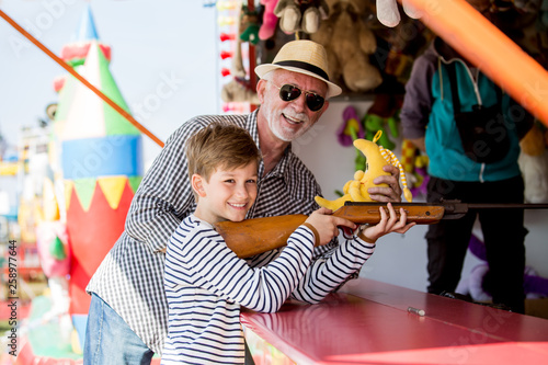 Little boy with grandfather having fun at amusement park