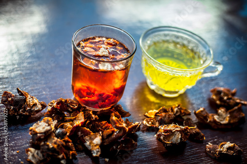 Raw organic amaltas or golden shower tree fruit on wooden surface with its extracted pulp in a glass along with water and green tea in a glass cup.Used for the treatment of worms in intestine. photo