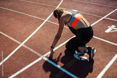 From above back view of teen athlete preparing for sprinting on track in starting position