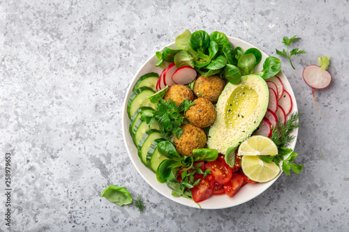 healthy vegan lunch bowl salad with avocado, falafel,cucumber, tomato and redish