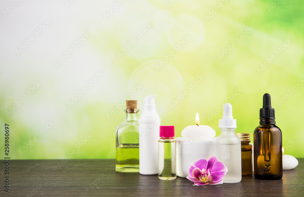 Composition with lot of different size, shape and material beauty cosmetics products bottles arrangement on wooden table with green bokeh studio background with lot of copy space. Composition with lot of different size, shape and material beauty cosmetics products bottles arrangement on wooden table with green bokeh studio background with lot of copy space.