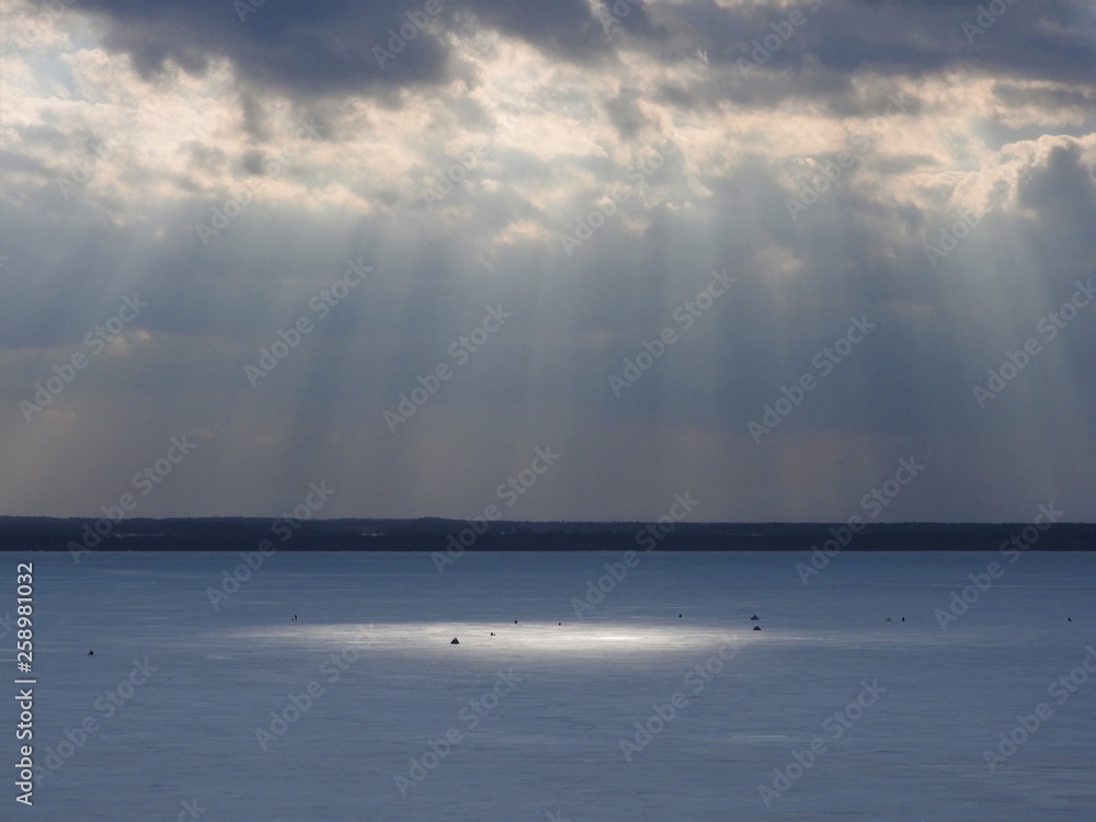 Fototapeta premium Ice frozen lake on a Sunny winter day in Russia. White snow and clouds in the blue sky. Beautiful winter landscape.