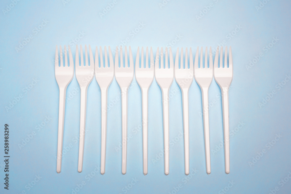 Single-use plastic products: plastic cutlery, cups on bright blue background Single-use plastic products: plastic cutlery, cups on bright blue background