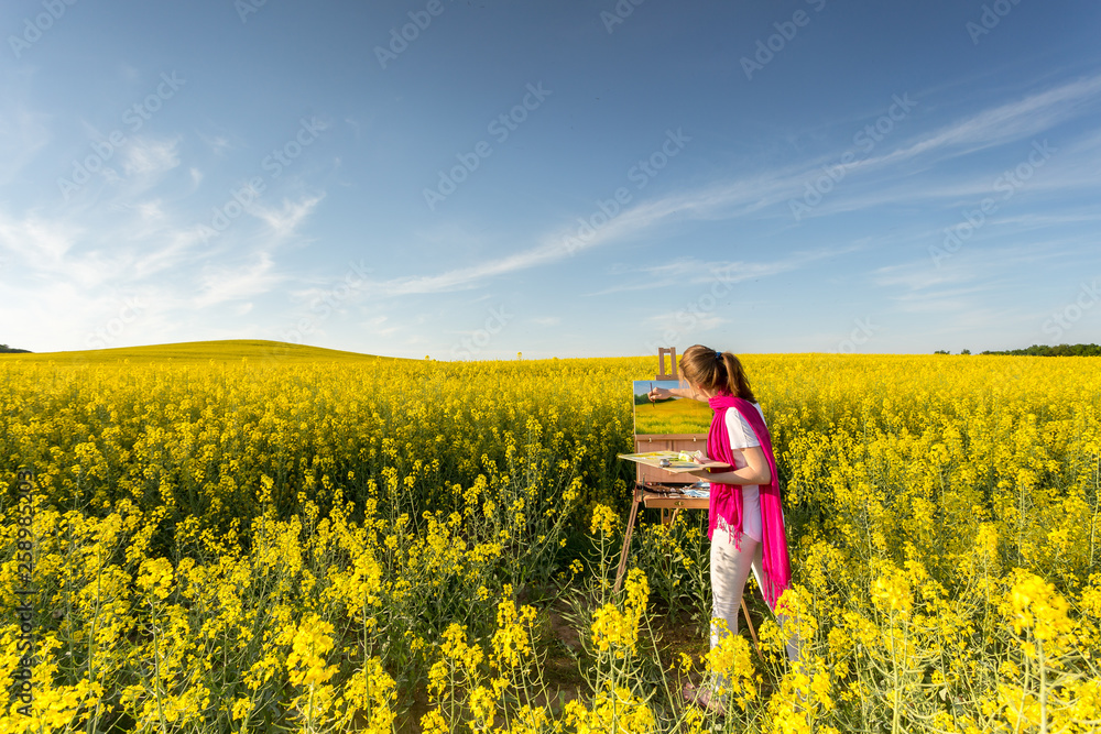 girl painter with an easel in a yellow rapeseed field girl painter with an easel in a yellow rapeseed field