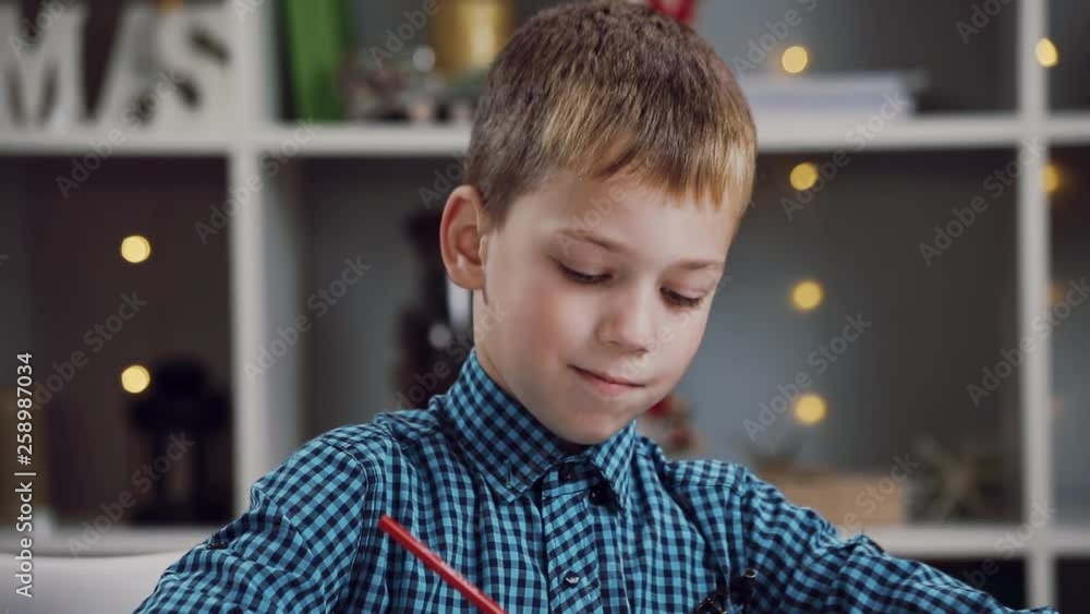 Close up view of handsome cheerful little boy in checkered shirt holding colored pencil, deciding what to draw. Enthusiastic cute preschool kid painting with colorful pencil in coloring book. Close up view of handsome cheerful little boy in checkered shirt holding colored pencil, deciding what to draw. Enthusiastic cute preschool kid painting with colorful pencil in coloring book.