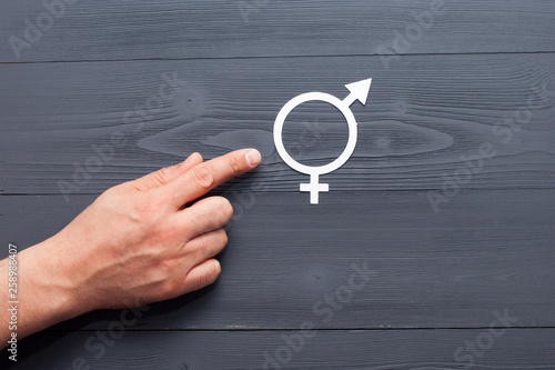 The man points his hand to the symbol of gender equality, the concept of gender equality. Black wooden background.
