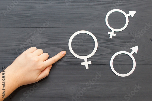 The women points his hand to the symbol of gender equality, the concept of gender equality. Black wooden background.