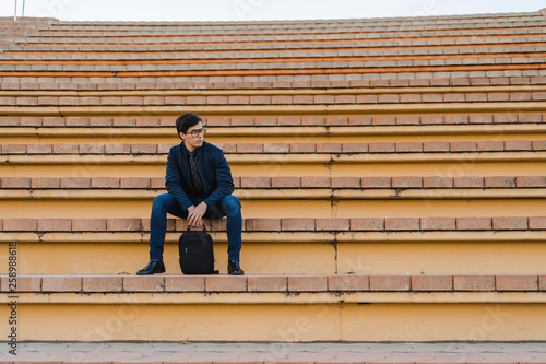 Wallpaper Mural Young businessman with backpack sitting on stairs looking at distance Torontodigital.ca