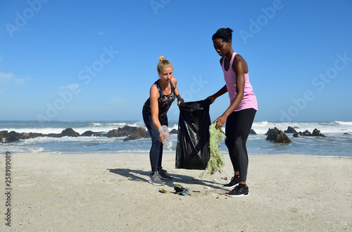 Two women cleaning the beach from plastic waste photo