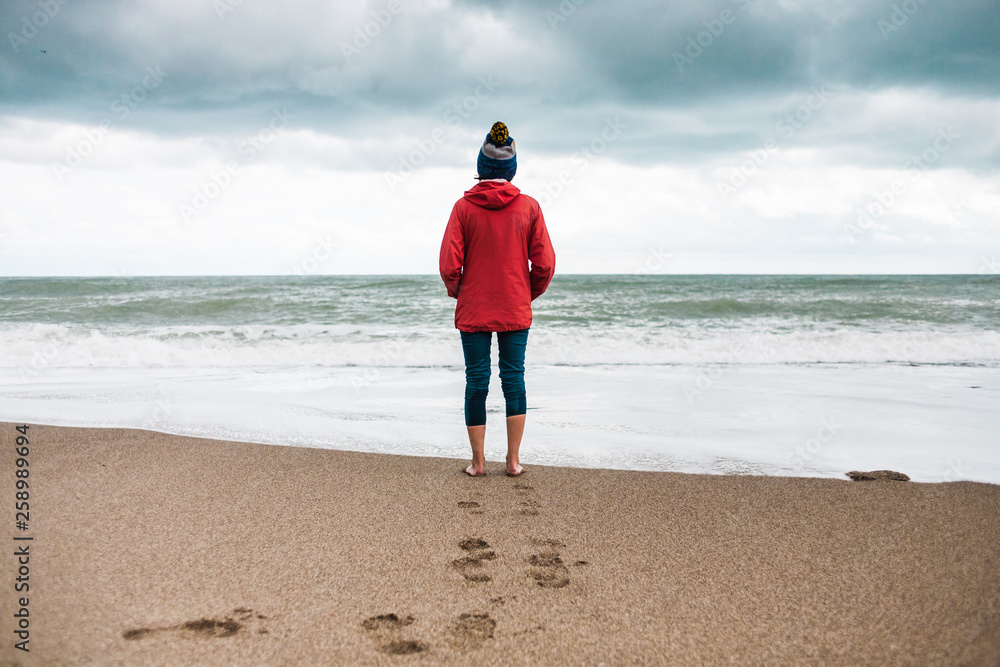 Barefoot woman looks at the winter sea.