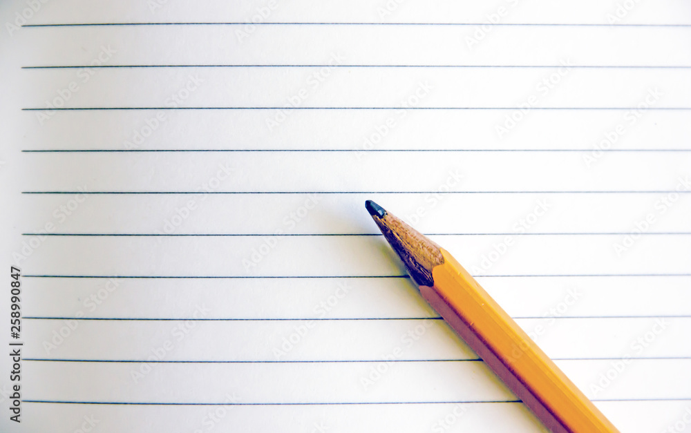 Pencil on a sheet in line.Back to school, education concept - orange pencil close up and composition book on background for educational new academic year begin or study term start. Mock-up Copy space Pencil on a sheet in line.Back to school, education concept - orange pencil close up and composition book on background for educational new academic year begin or study term start. Mock-up Copy space