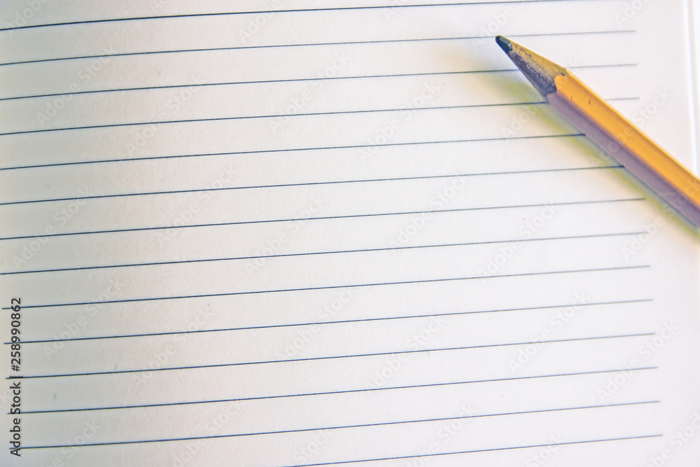 Pencil on a sheet in line.Back to school, education concept - orange pencil close up and composition book on background for educational new academic year begin or study term start. Mock-up Copy space Pencil on a sheet in line.Back to school, education concept - orange pencil close up and composition book on background for educational new academic year begin or study term start. Mock-up Copy space