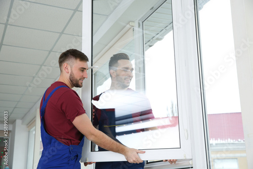 Construction workers installing plastic window in house