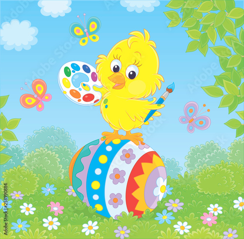 Little yellow chick coloring an Easter egg among flowers on green grass of a lawn on a sunny spring day, vector illustration in a cartoon style
