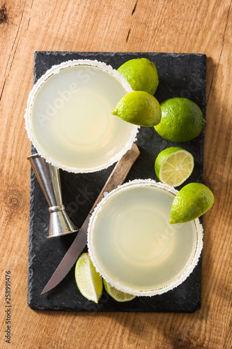 Margarita cocktails with lime in glass on wooden table. Top view